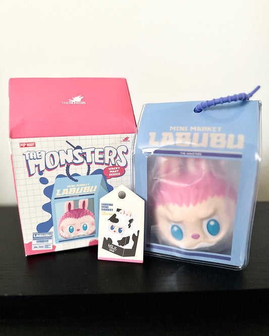 Lalubu toy with packaging and card on a black surface