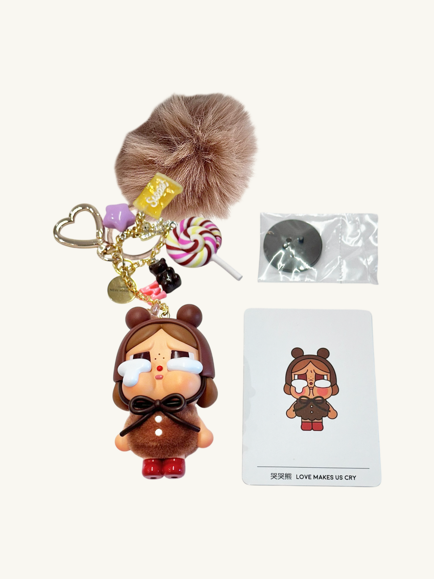 Keychain with plush character, lollipop charm, and packaging on a white background