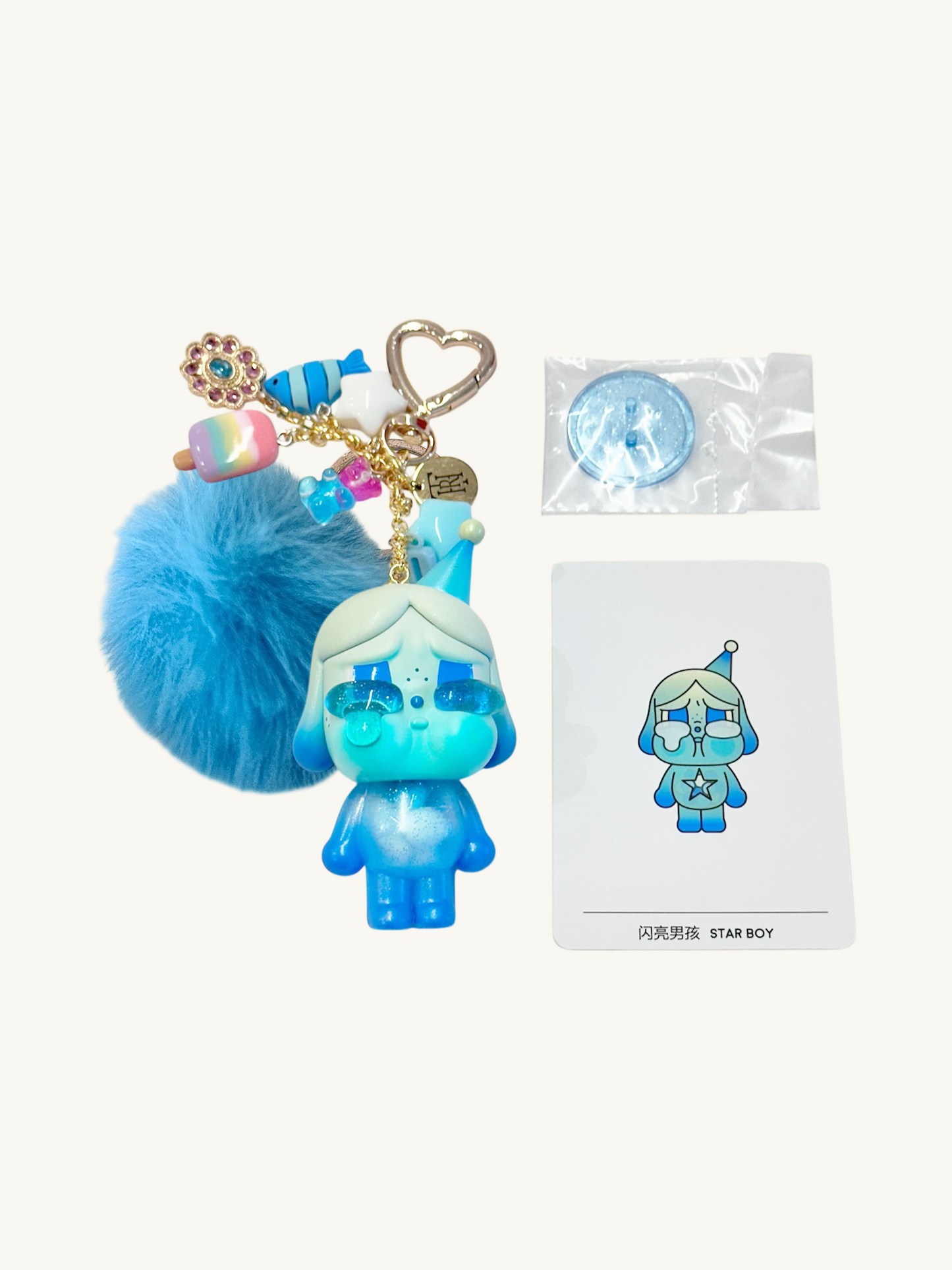 Blue character keychain with fluffy attachment and heart-shaped tag on a white background