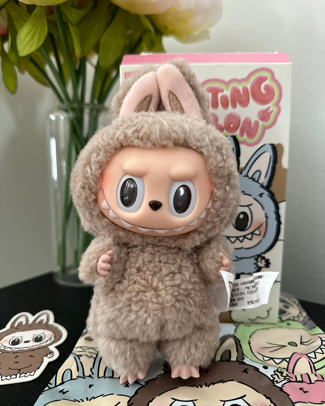 Plush toy in a costume with a box labeled 'Ting' in the background