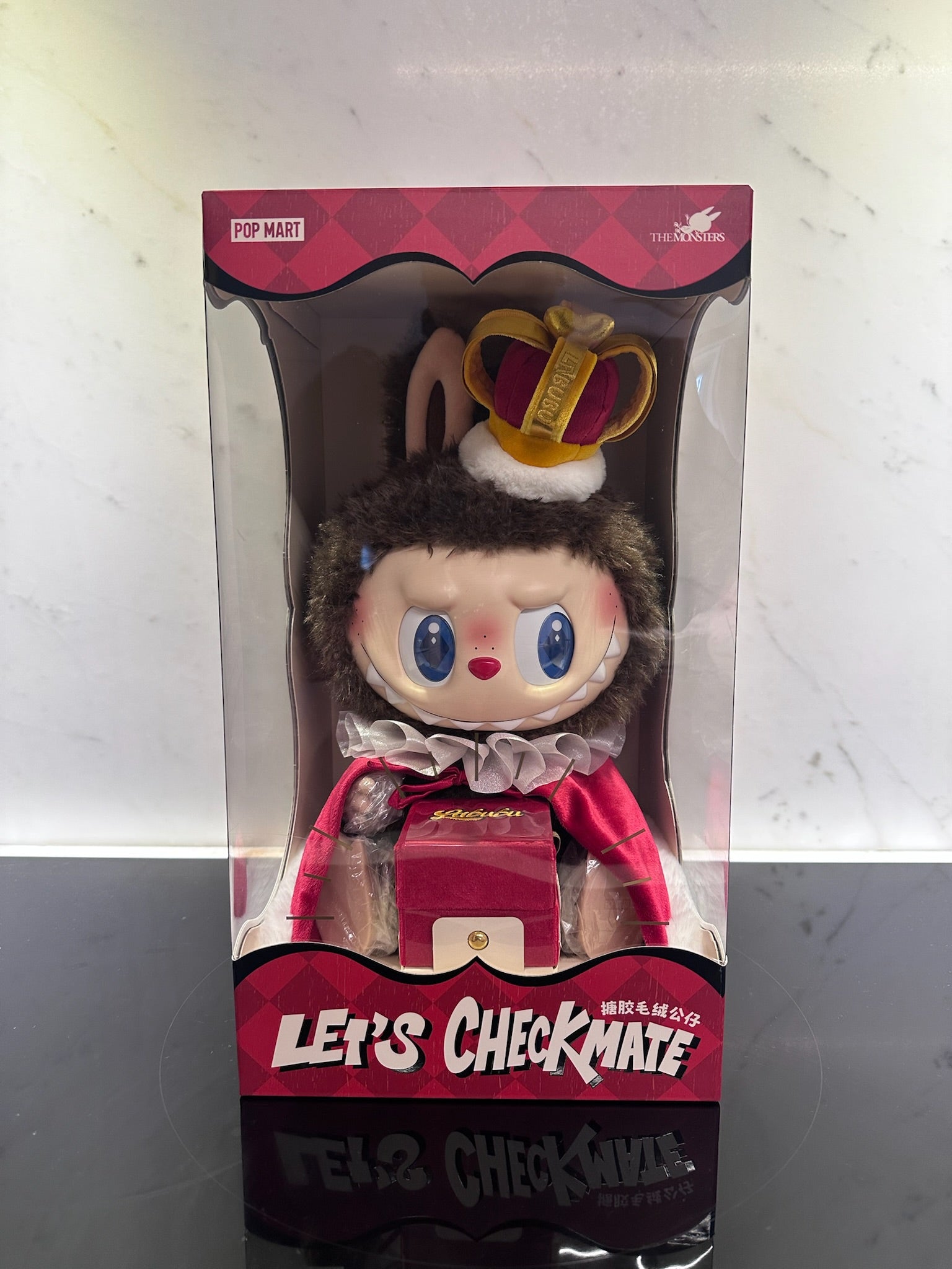 Toy figure in a box with a crown and red outfit, brand 'Pop Mart' visible