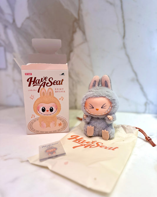 Plush toy with packaging and branded pouch on a light background