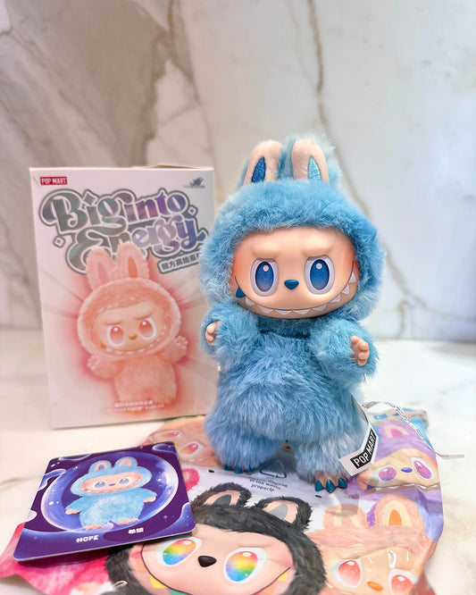 Blue plush toy with bunny ears and a box labeled 'Big into Sweetie' on a white surface.