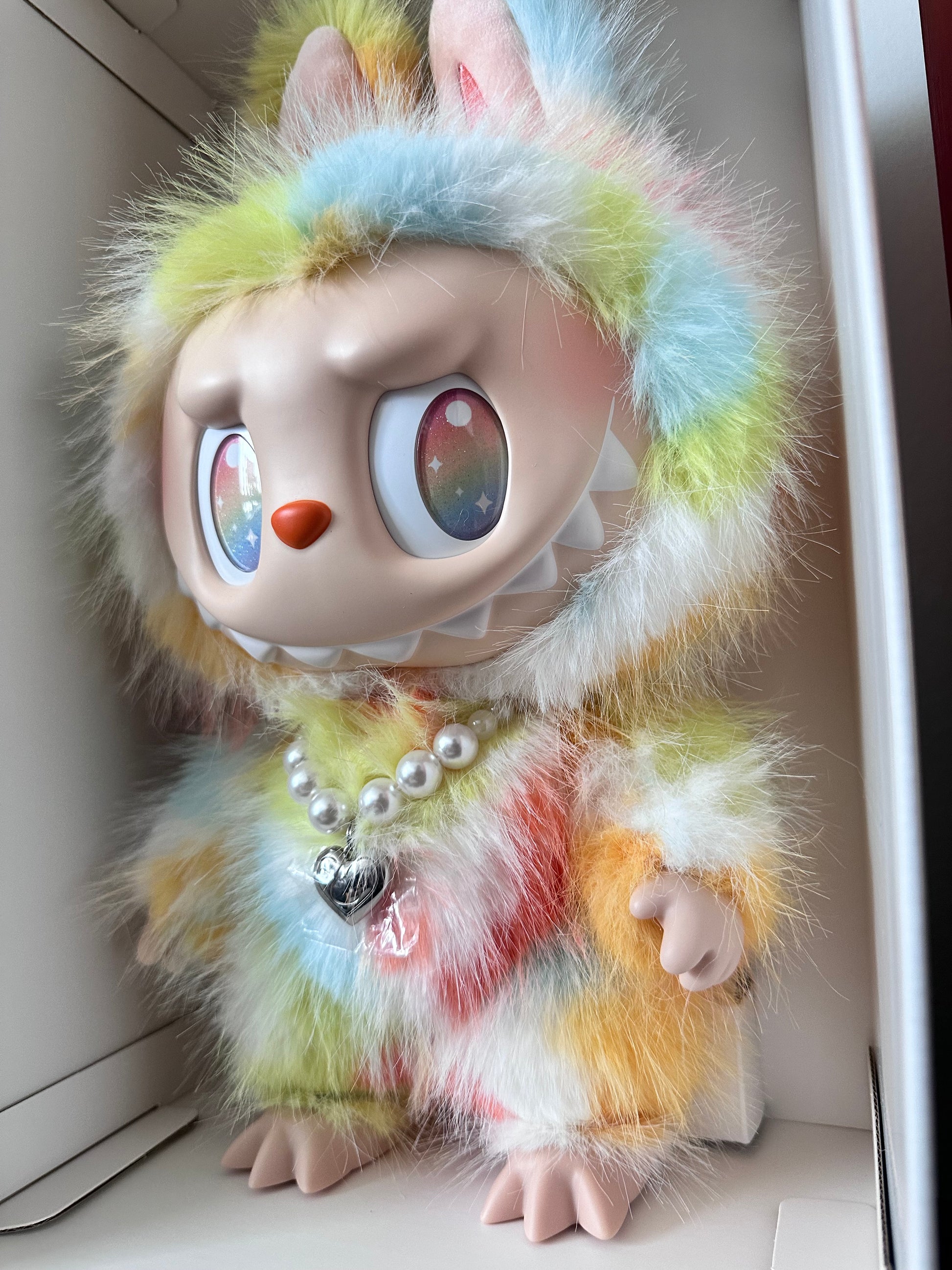 Toy with colorful fur and a face on a white surface