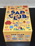 Box of 'Sad Club' with colorful illustrations on a dark surface