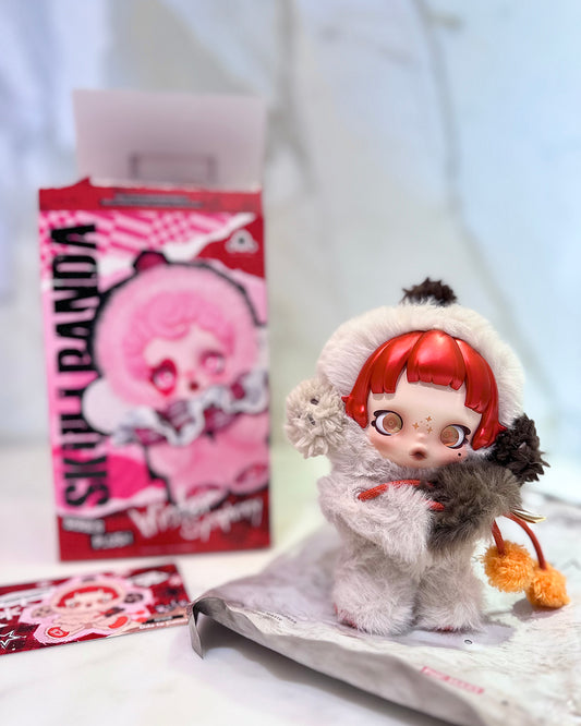 Toy figure with red hair and white outfit in front of a pink box with cartoon character