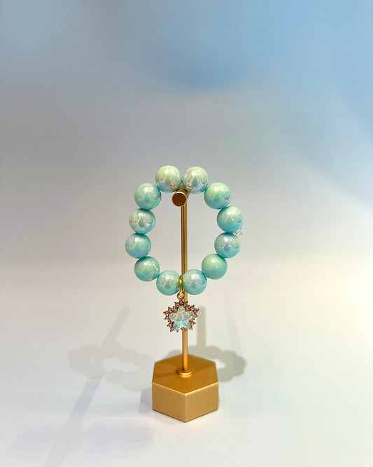 Turquoise beaded bracelet on a gold stand with a light blue background