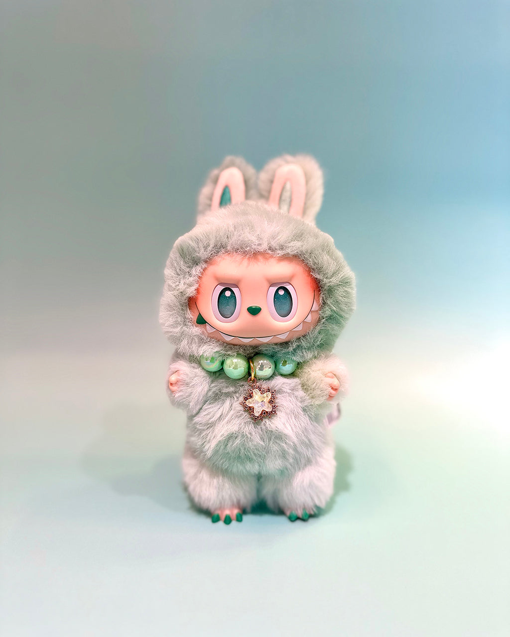 Plush toy with bunny ears and a soft gray outfit on a gradient background