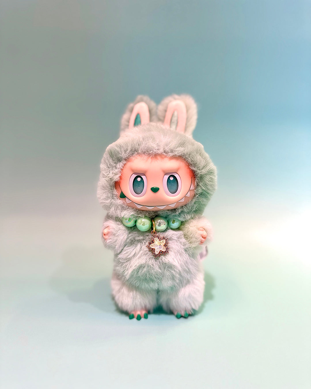 Plush toy with bunny ears and a soft gray outfit on a gradient background