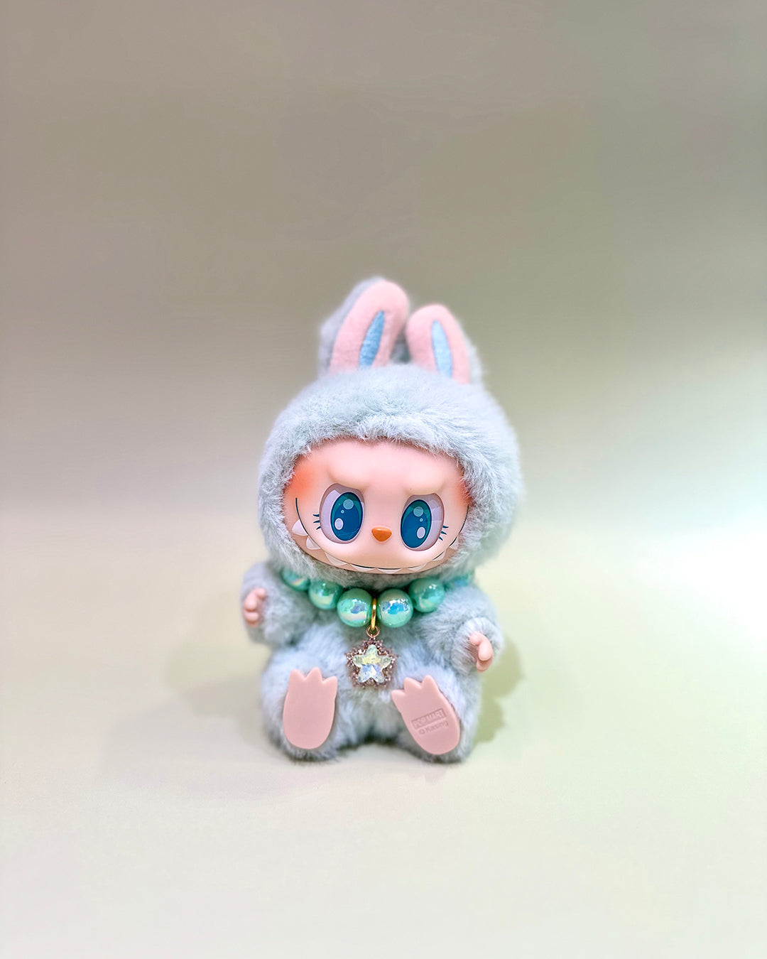 Toy figure with bunny ears and a fluffy gray outfit on a light background