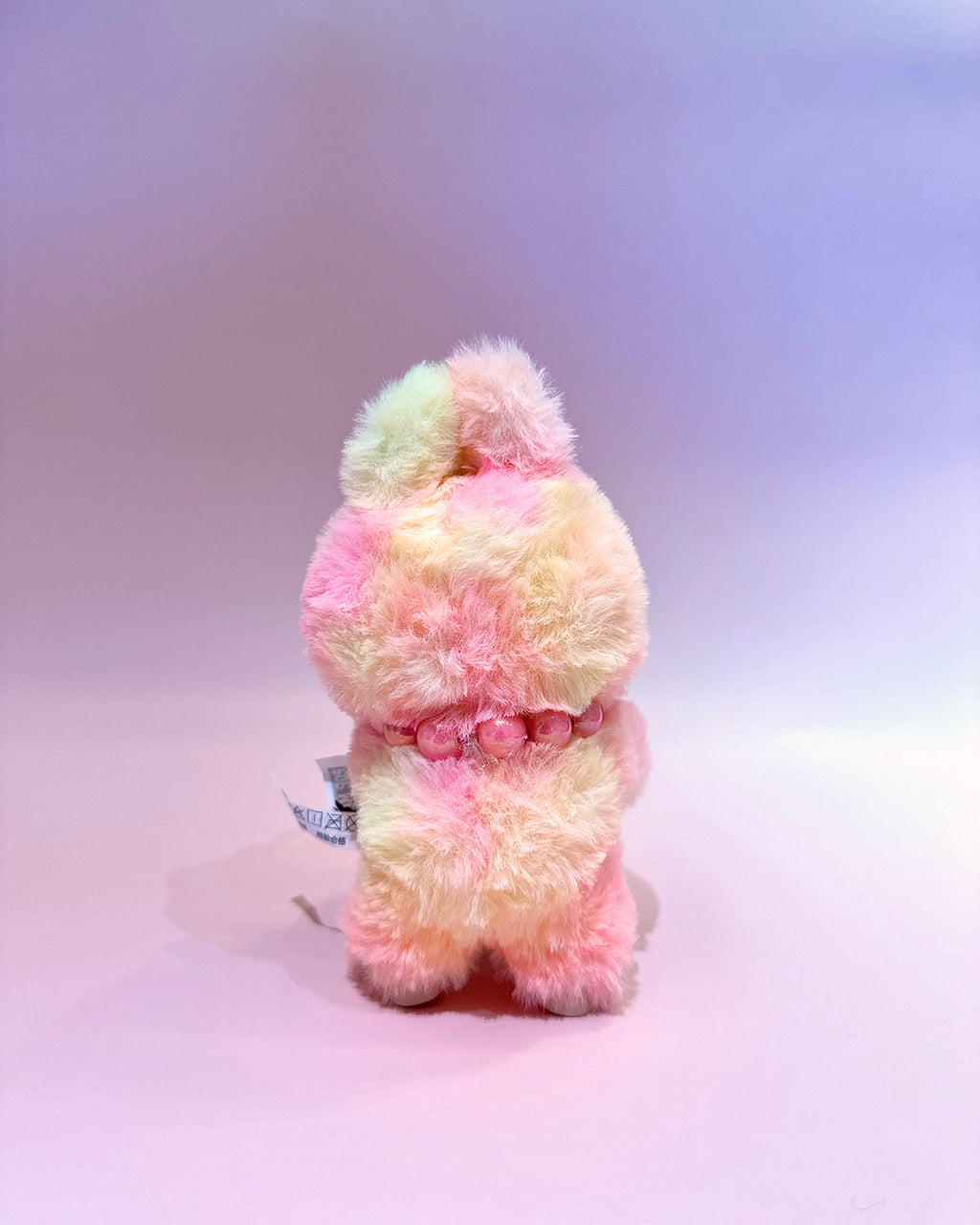 Pastel-colored plush toy on a light purple background