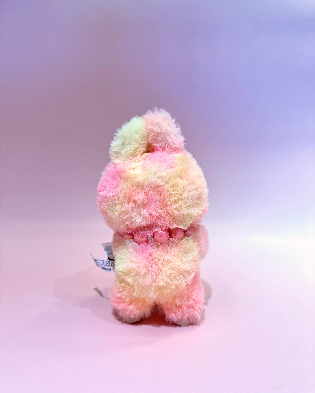 Pastel-colored plush toy on a light purple background