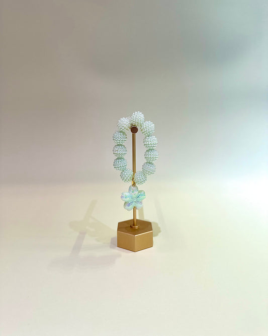 Decorative wreath with greenery on a gold stand against a neutral background