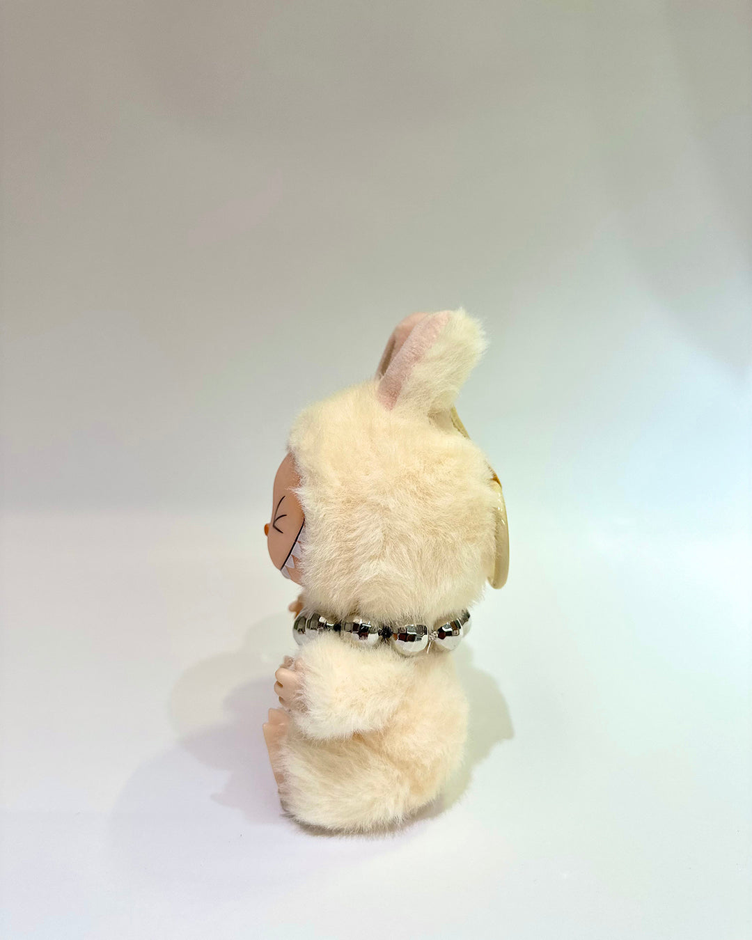 Plush toy with a fluffy white head and body on a light gray background