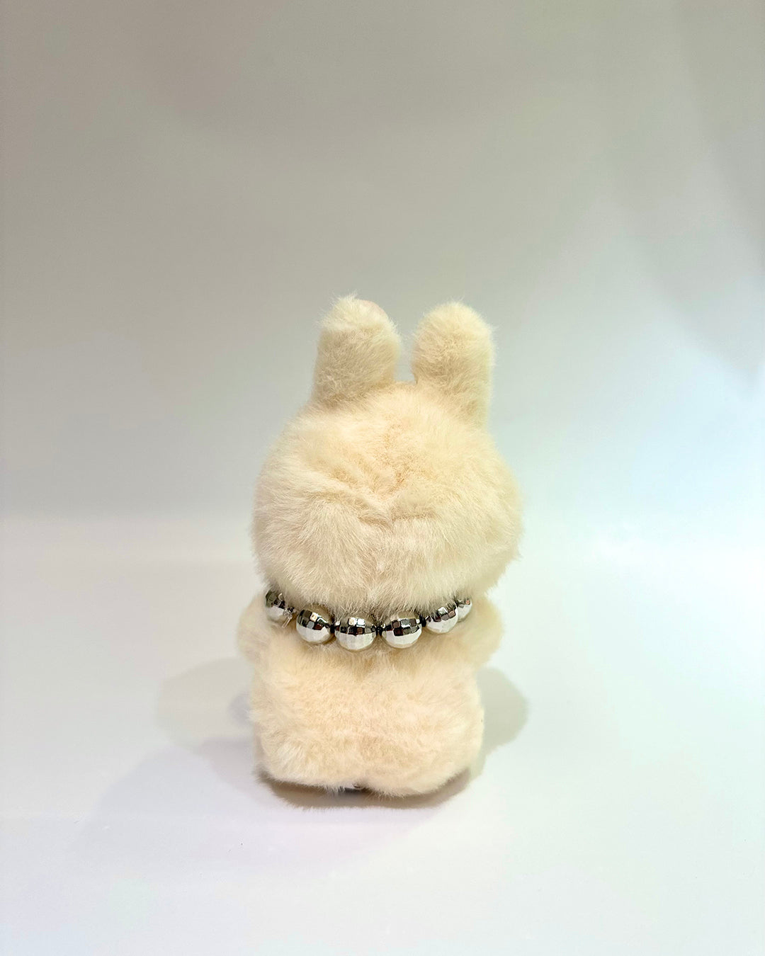 Plush toy with a pearl necklace on a white background