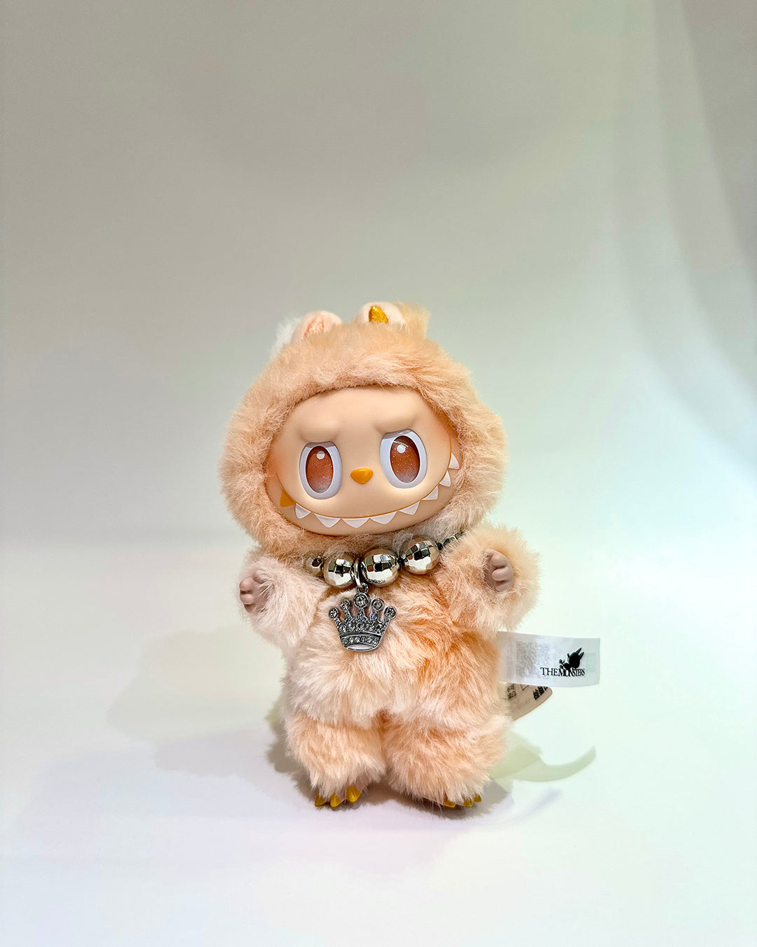 Plush toy with a hood and tag on a white background