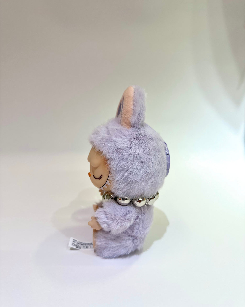Plush toy resembling a character with a fluffy gray hood on a white background