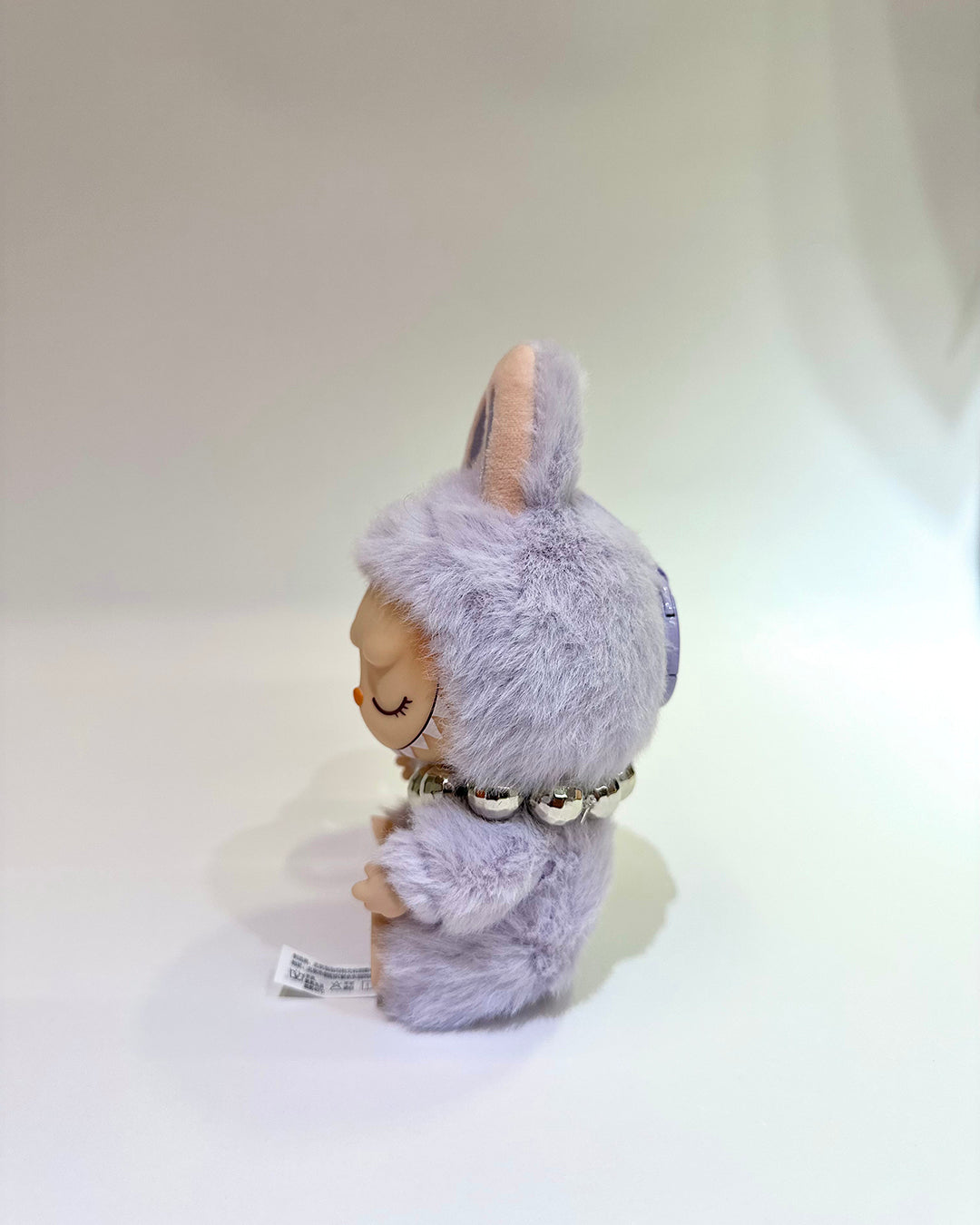 Plush toy resembling a character with a fluffy gray hood on a white background
