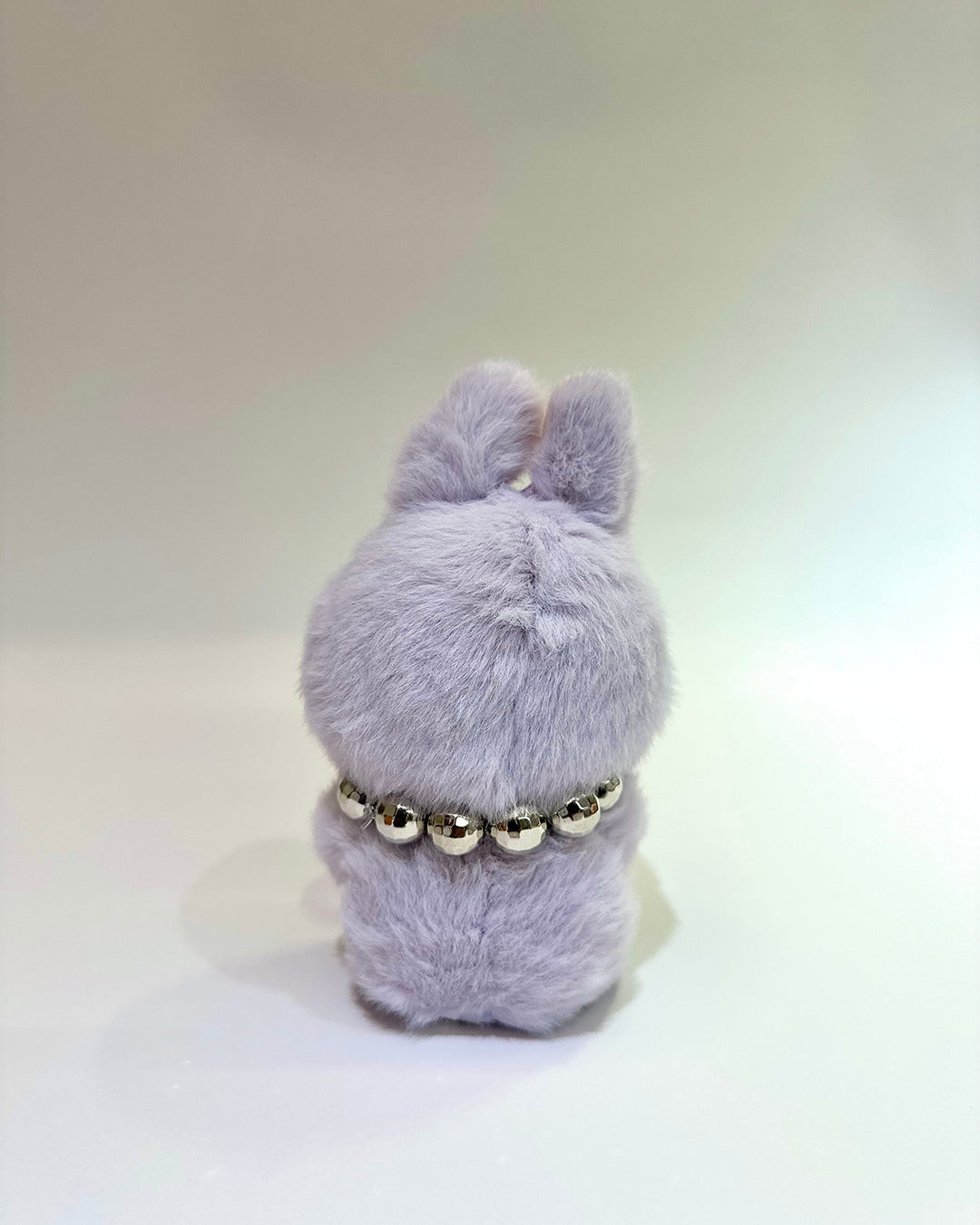 Gray plush toy with a necklace on a white background