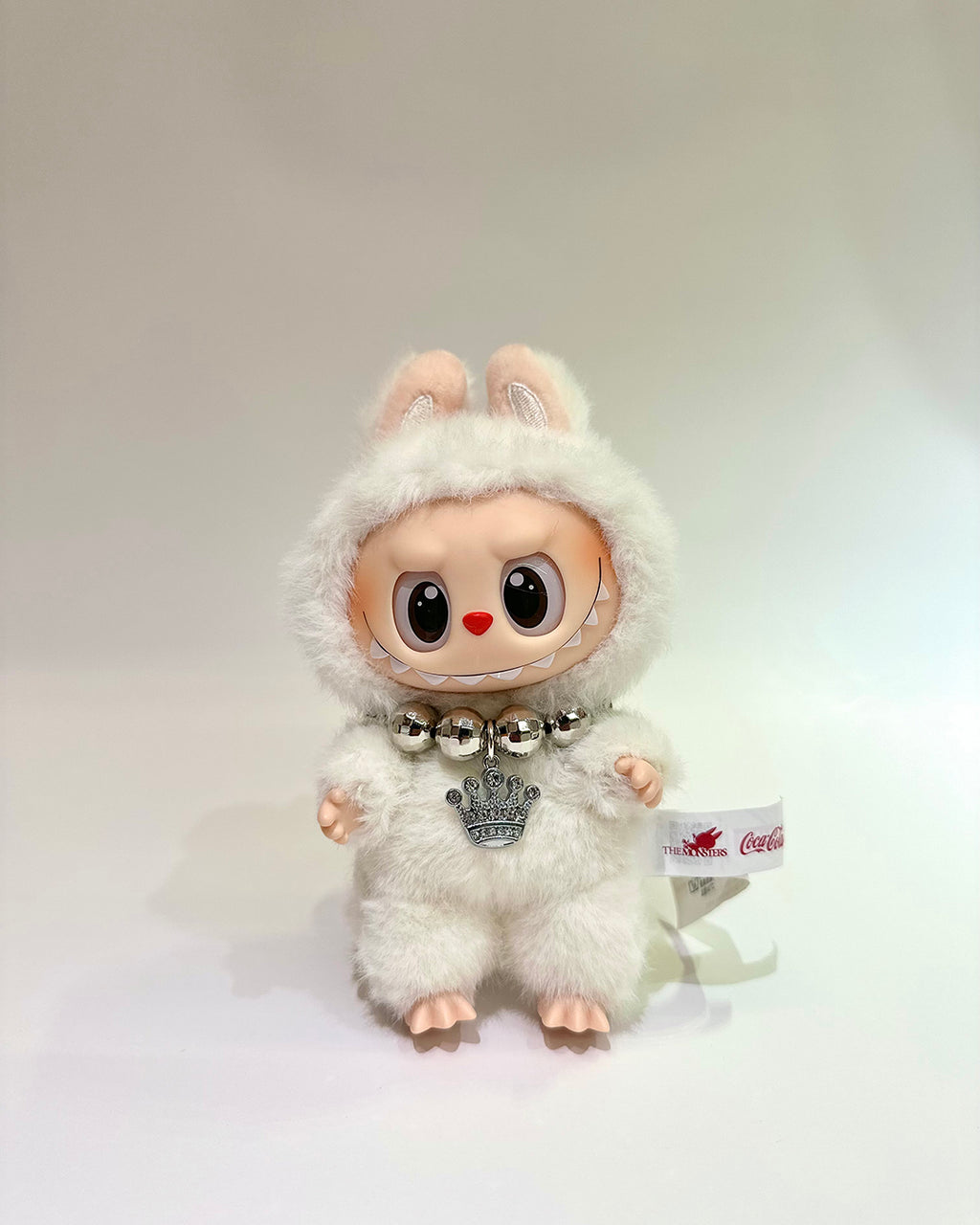 White plush toy with a fluffy hood and bell on a white background