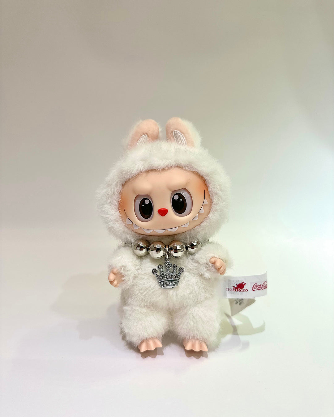 White plush toy with a fluffy hood and bell on a white background