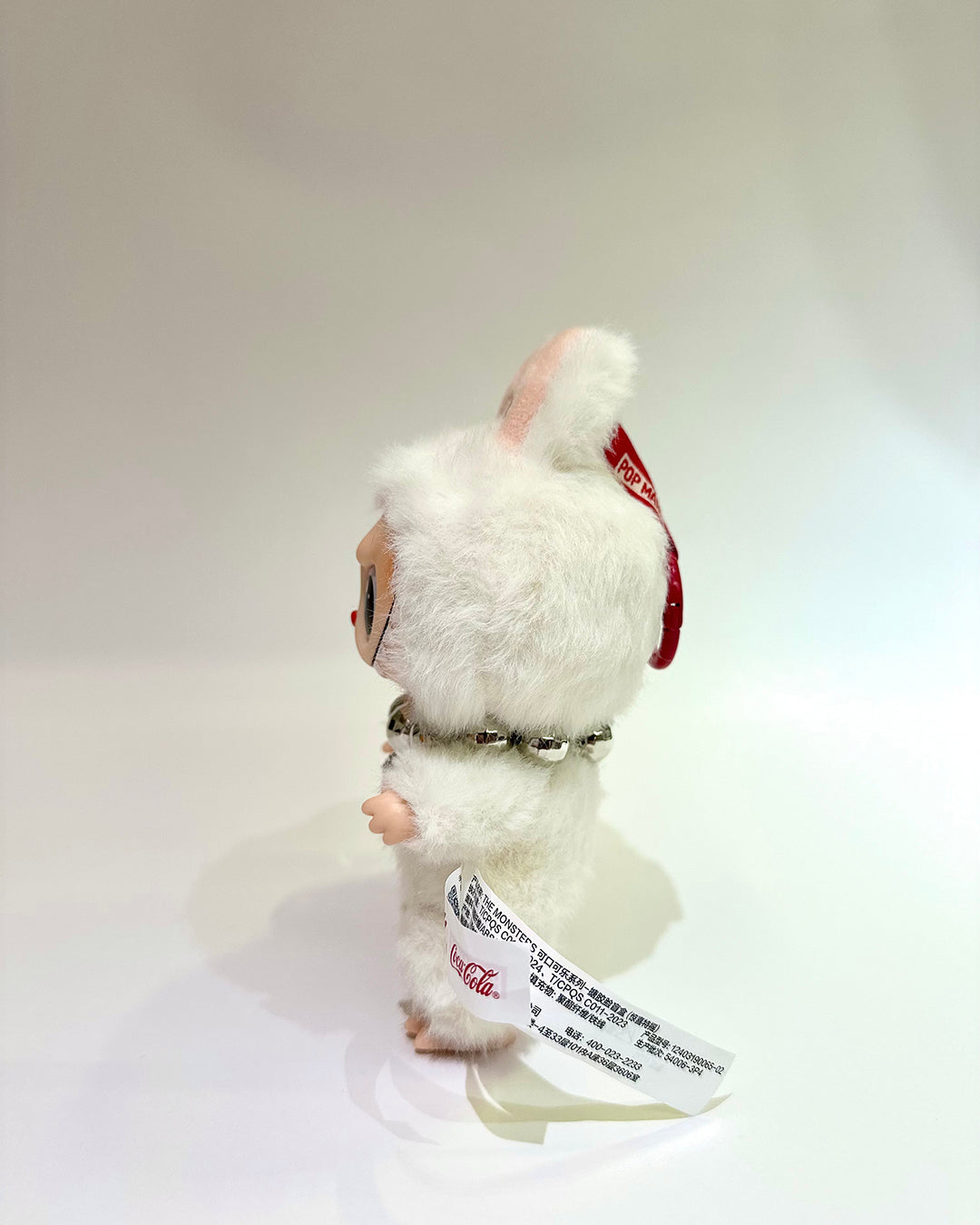 White plush toy with a red bow on a white background