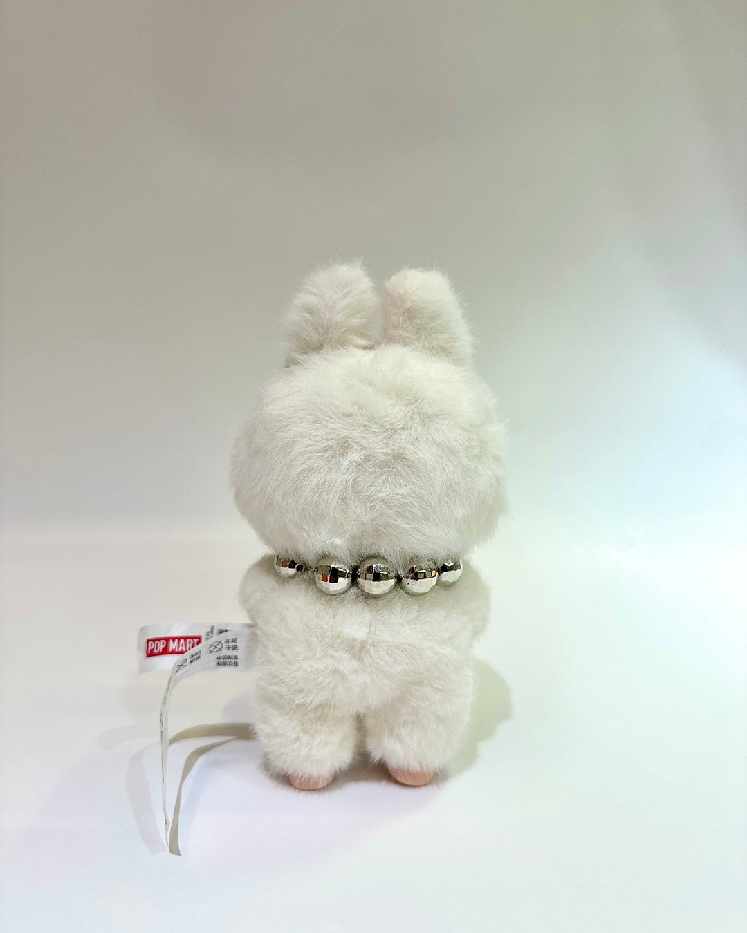 White fluffy toy with a silver collar on a white background