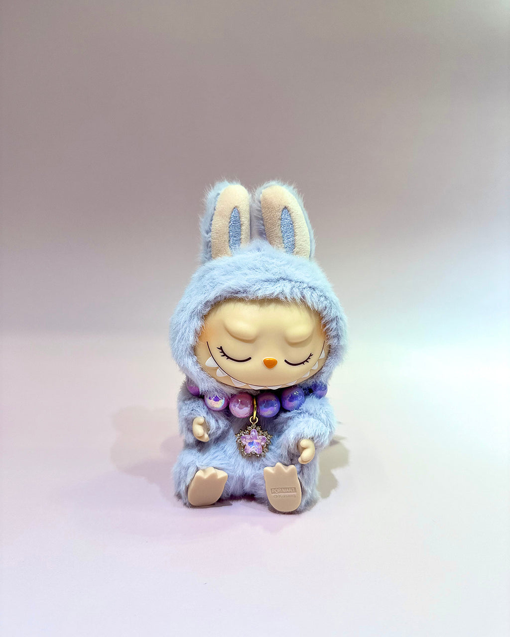 Plush toy with a blue hood and rabbit ears on a light gray background