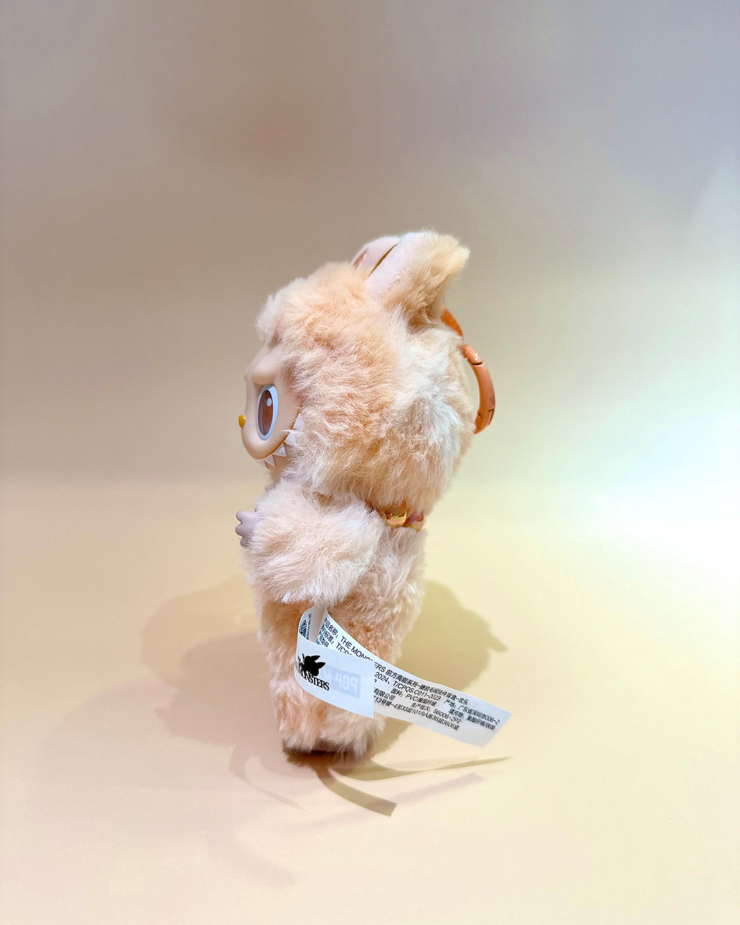 Small plush toy with a tag on a beige background