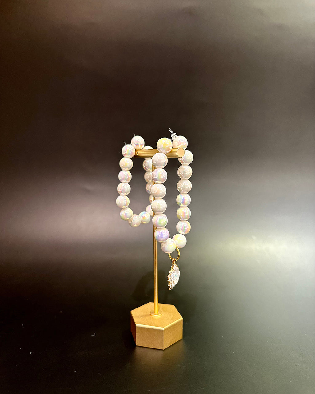 Pearl bracelet on a gold stand against a dark background