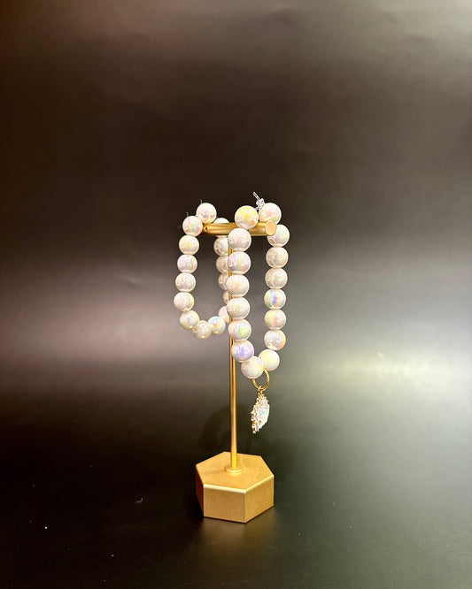 Pearl bracelet on a gold stand against a dark background