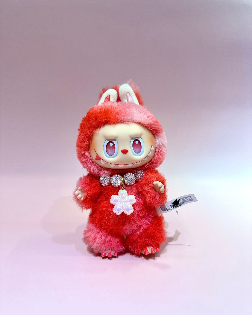 Plush toy with red fur and bunny ears on a light gray background