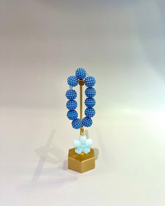 Decorative object with blue beaded design on a gold stand against a light gray background