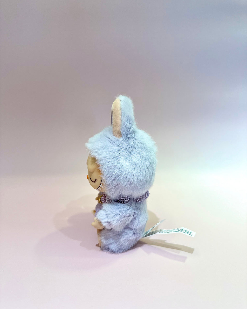 Small figurine with a fluffy blue hood on a plain background