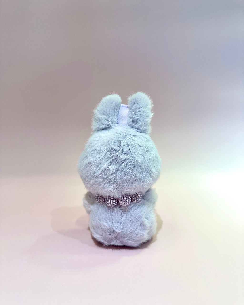 Light blue plush toy with a bow on a light gray background
