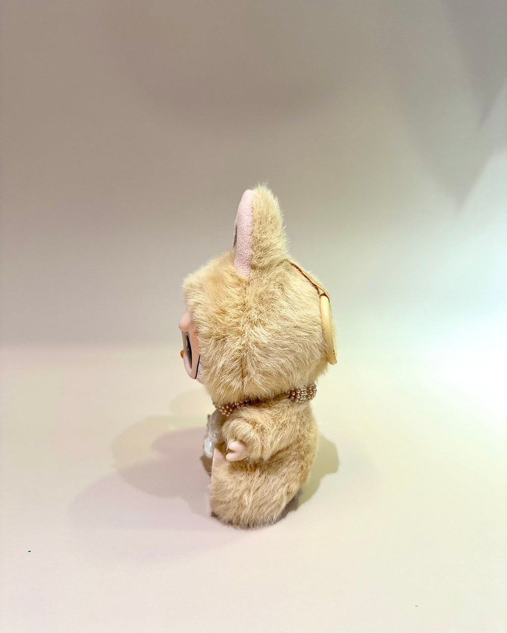 Plush toy resembling a rabbit with a pink bow on a plain background