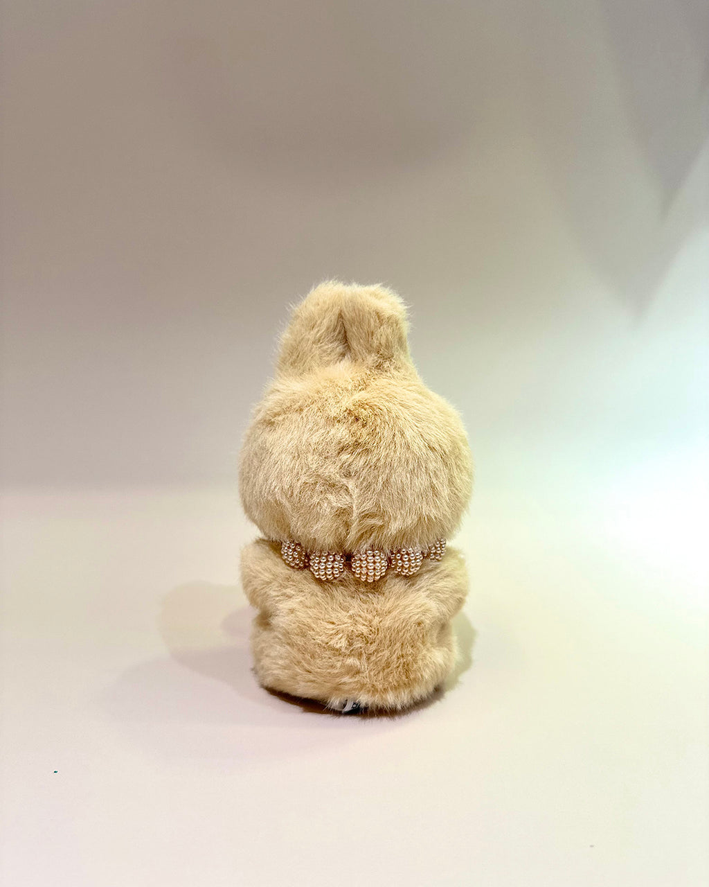 Beige teddy bear with a decorative ribbon on a white background