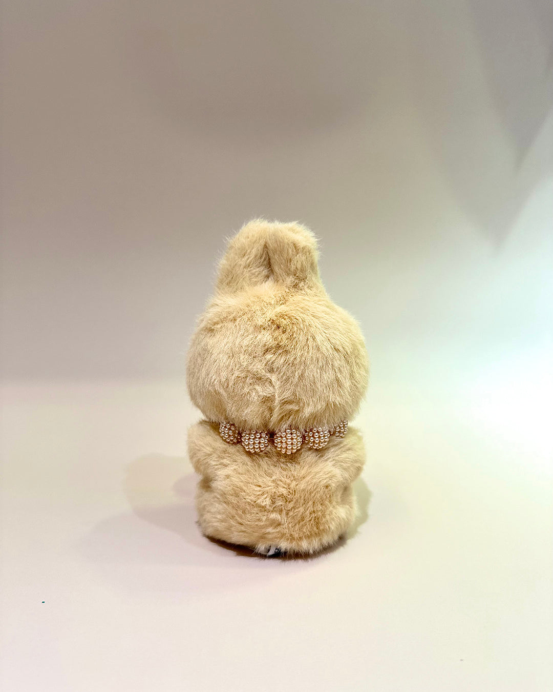 Beige teddy bear with a decorative ribbon on a white background