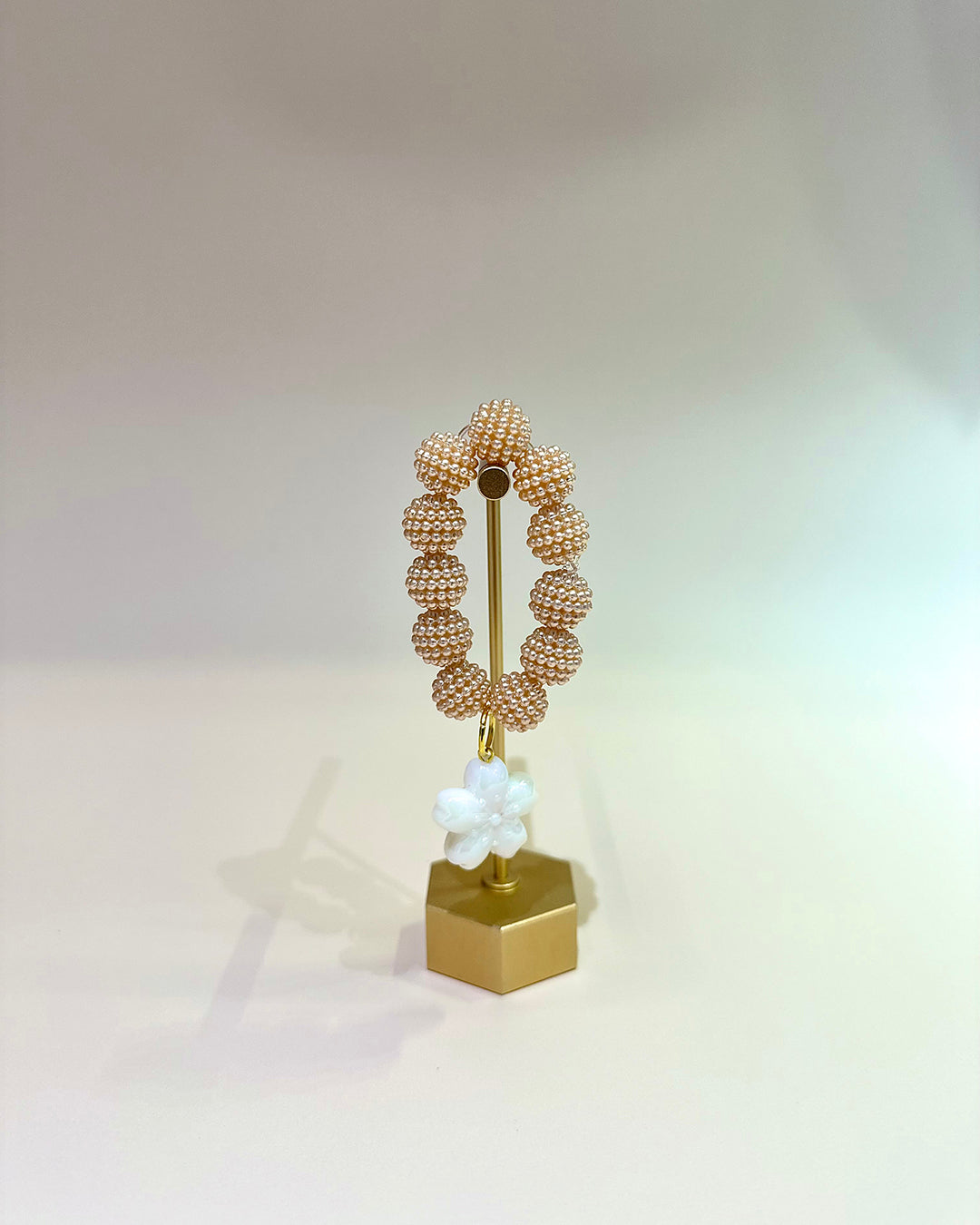Decorative object with beaded design on a gold stand against a light background