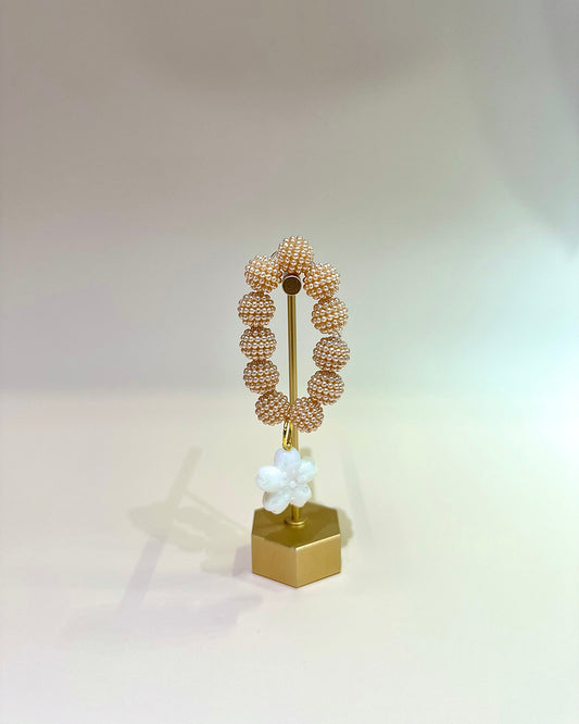 Decorative object with beaded design on a gold stand against a light background