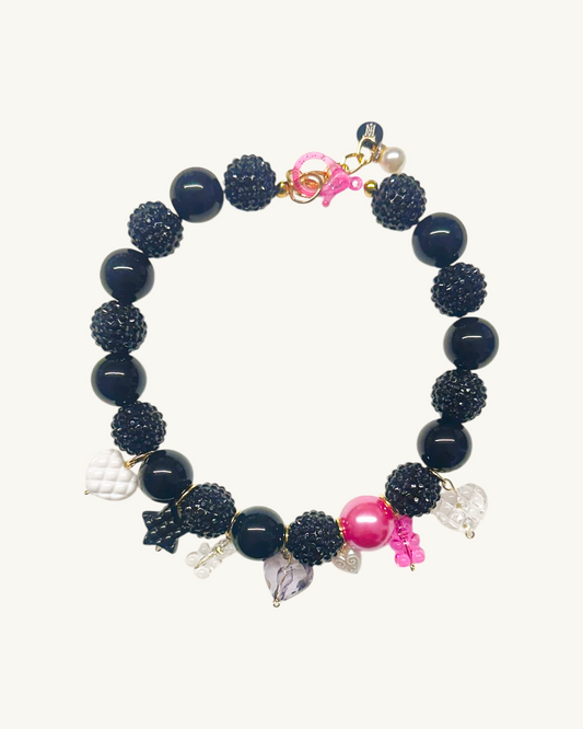 Black beaded bracelet with pink and clear charms on a white background