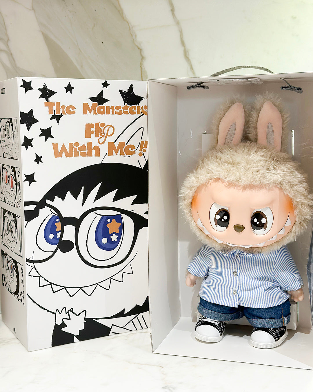 Toy figure with bunny ears in a box with a cartoon face design on the packaging.