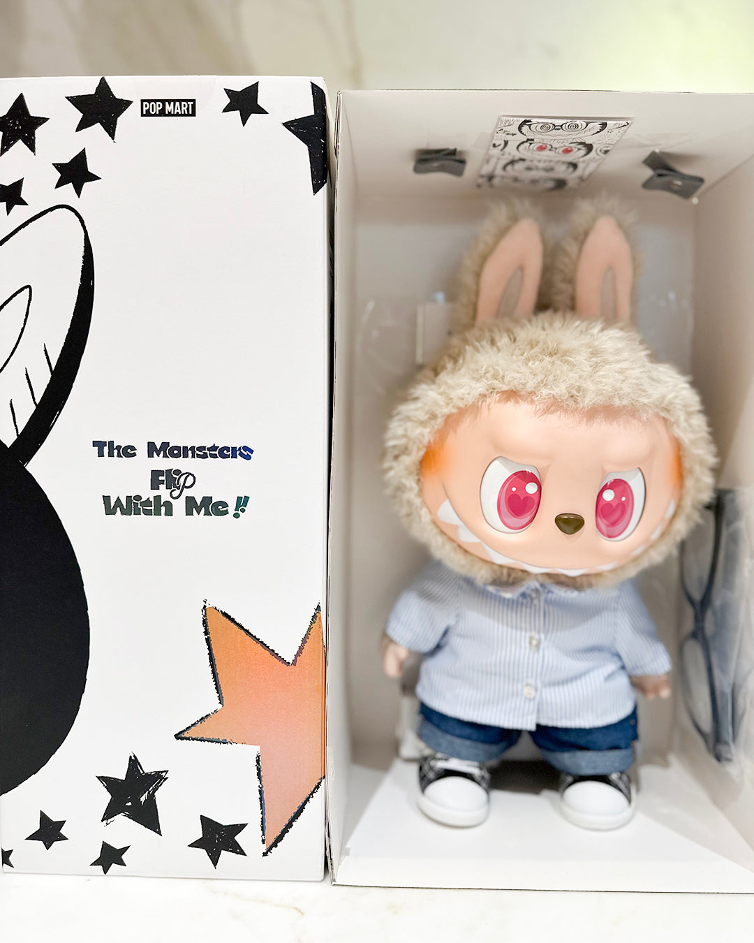 Plush toy with bunny ears in a box with branding and text