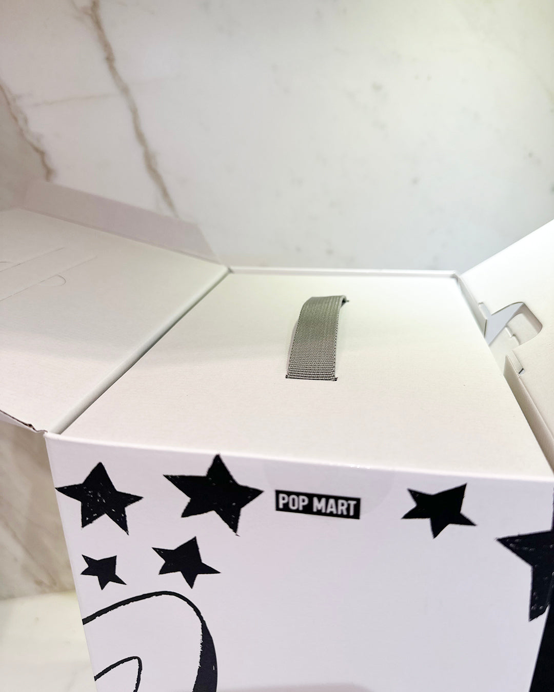 White box with black star designs and 'POP MART' branding on a white background