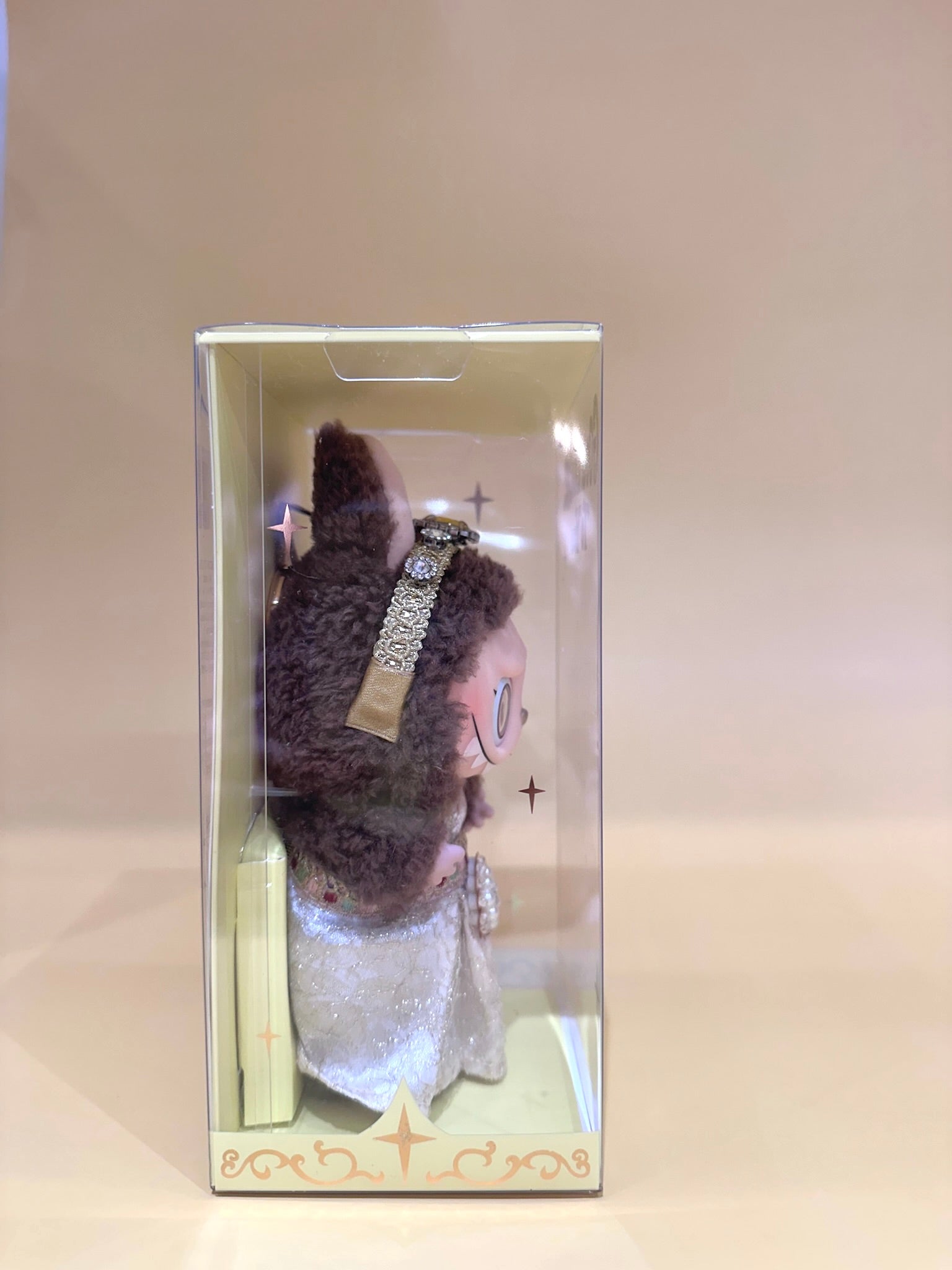 Stuffed animal toy in a clear packaging box on a beige background