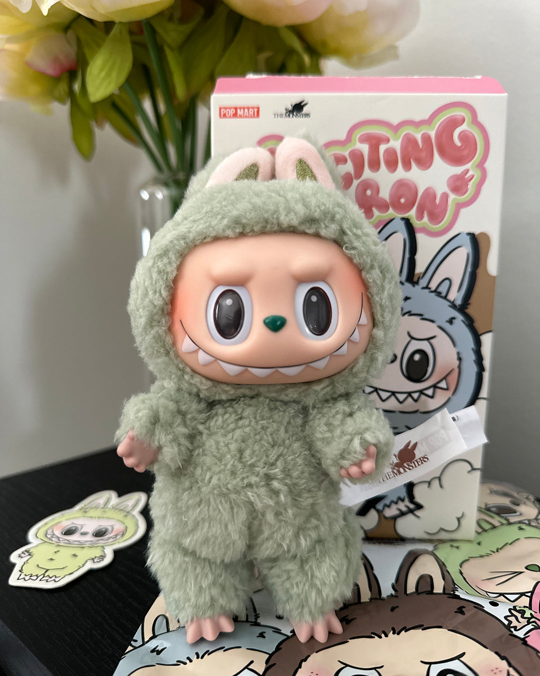 Plush toy in a green costume with a box labeled 'Futina' in the background.