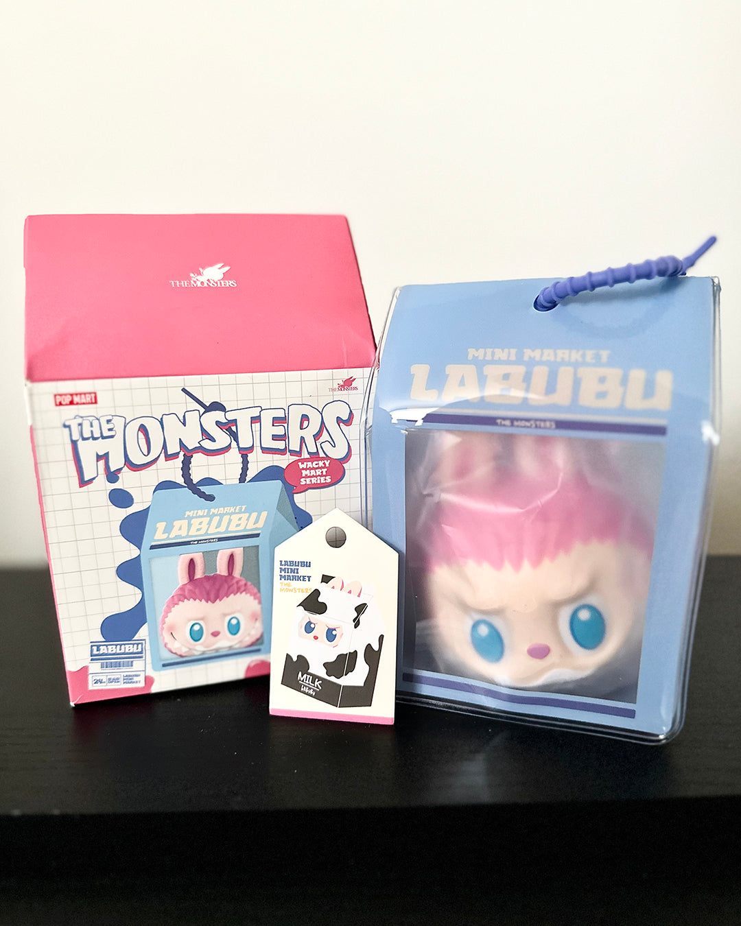 Lalubu toy with packaging and card on a black surface