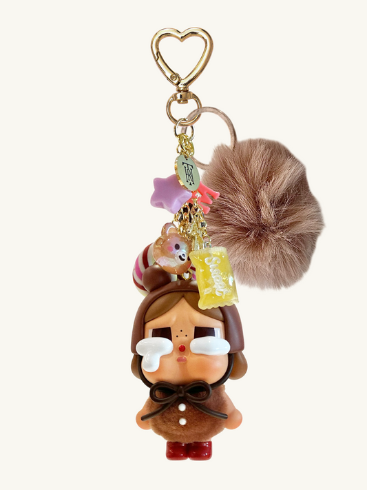 Keychain with cartoon character, pom-pom, and heart-shaped charm on a white background