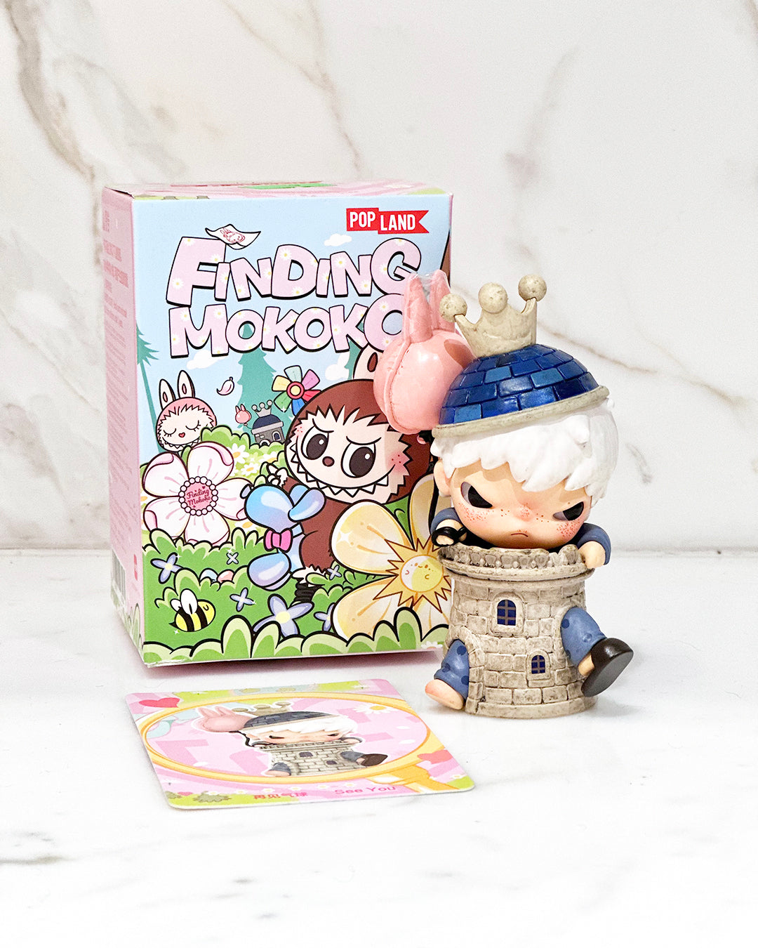 Toy figure of a character with a castle on a white background, next to a 'Finding Mokoko' box.