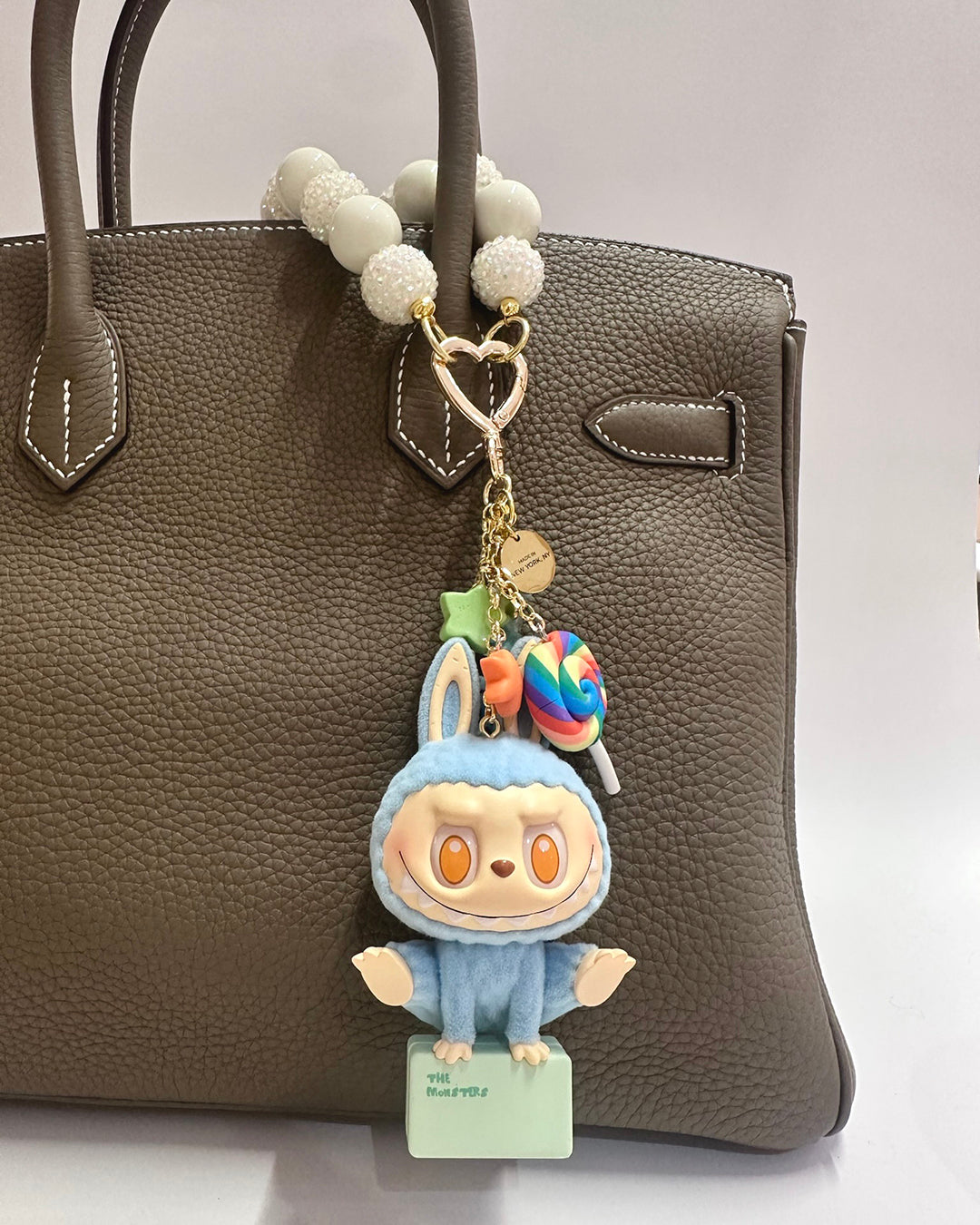 Cartoon character keychain with a lollipop on a brown handbag